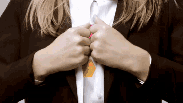 a woman in a suit and white shirt adjusts her tie