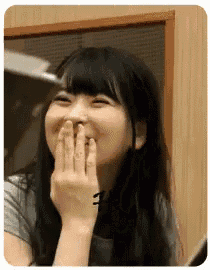 a woman is covering her mouth with her hand while laughing .