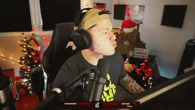 a man wearing headphones is sitting in front of a microphone in front of a sign that says daily strangest kick butt