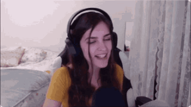 a woman wearing headphones and a yellow shirt is laughing