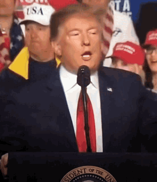 a man in a suit and tie is speaking into a microphone in front of a podium that says president of the unite states