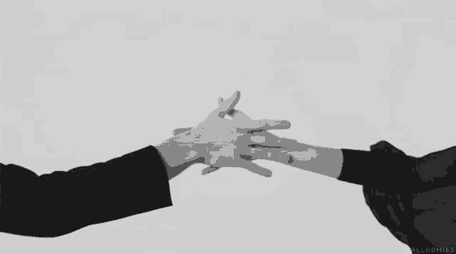 a black and white photo of two people holding hands