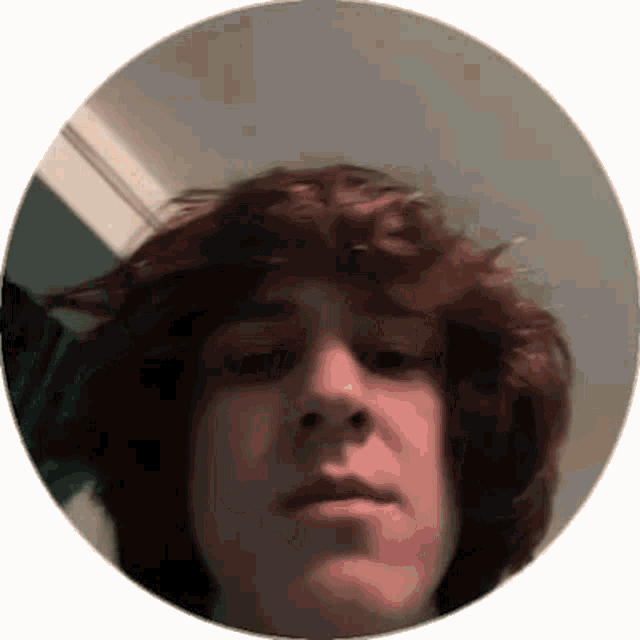 a young man with red hair is taking a selfie in a circle with his hair blowing in the wind .