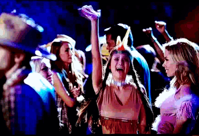 a woman in a native american costume is dancing with her hands in the air