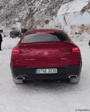 a red mercedes is parked in the snow