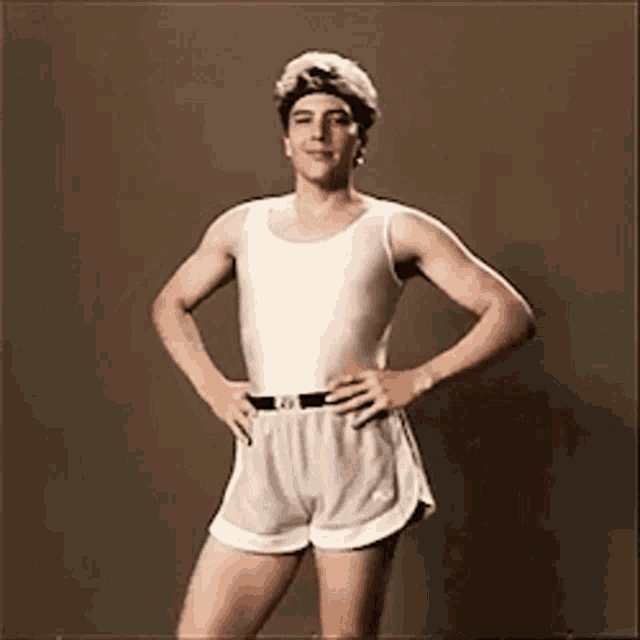 a man in a white tank top and shorts with a calvin klein belt