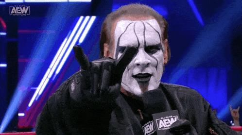 a wrestler giving a peace sign while holding a card that says aew on it
