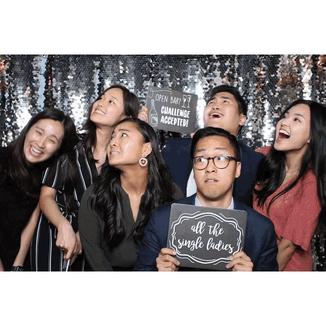 a group of people pose in a photo booth with one man holding up a sign that says all the single ladies