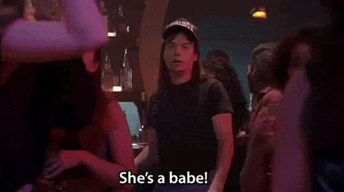 a man in a hat is standing in a crowd and says she 's a babe .