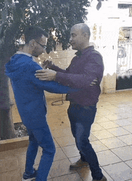 a man in a blue hoodie is standing next to a man in a purple shirt