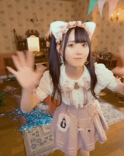 a girl wearing a cat ear headband is waving