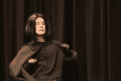 a man in a costume is standing in front of a black curtain .