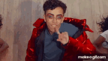 a man in a red jacket is pointing his finger at the camera