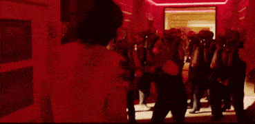 a group of people are standing on a red carpet in a dark room .