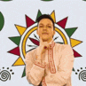 a man in a red and white shirt is holding his hands up in front of a colorful background .