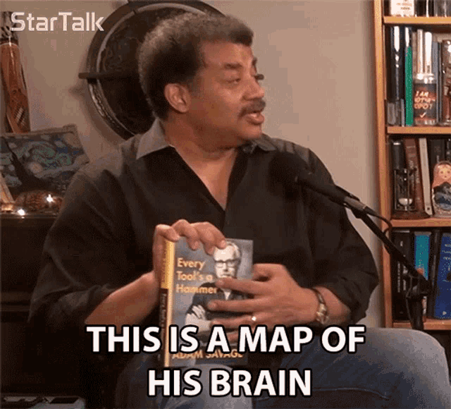 a man is holding a book and says this is a map of his brain