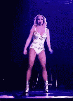 a woman is dancing on a stage in front of a microphone .