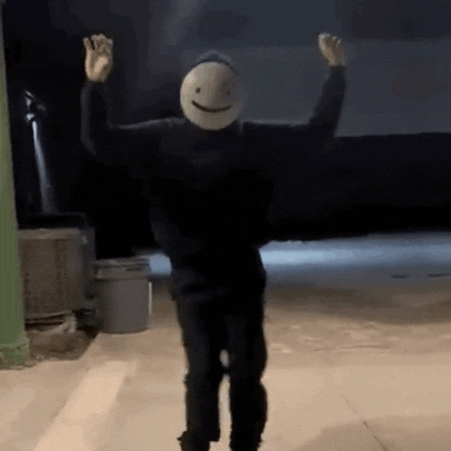 a person wearing a mask with a smiley face on it is dancing in a dark room .