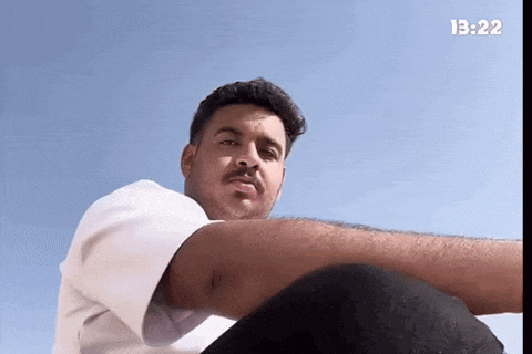 a man is sitting in front of a blue sky with the time 13:22
