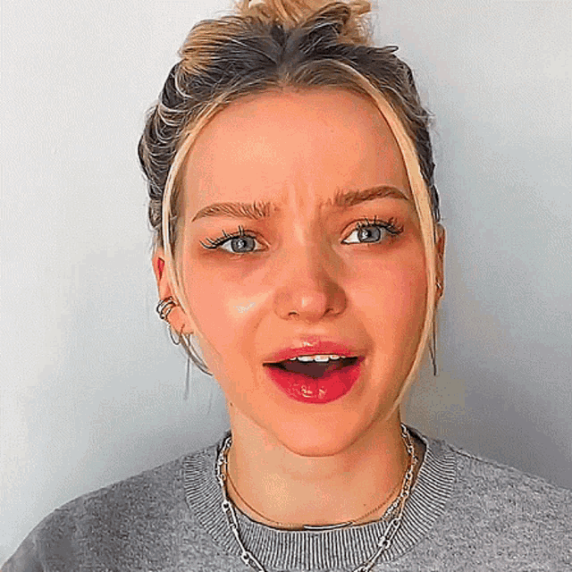 a close up of a woman 's face with her mouth open and a bun in her hair