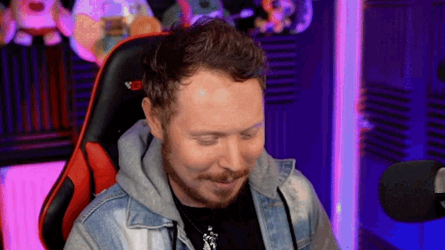 a man with a beard is sitting in a chair in front of a microphone with his eyes closed .