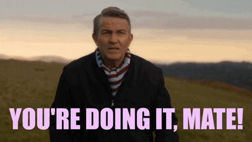a man is standing in a field with the words " you 're doing it mate "
