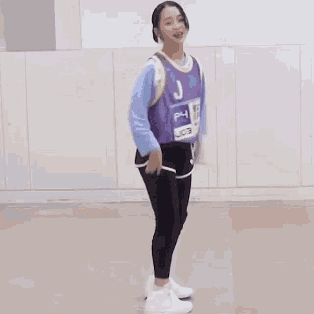 a girl in a purple shirt and black pants is dancing .