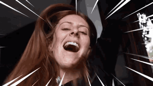 a woman with long red hair is laughing with her mouth wide open
