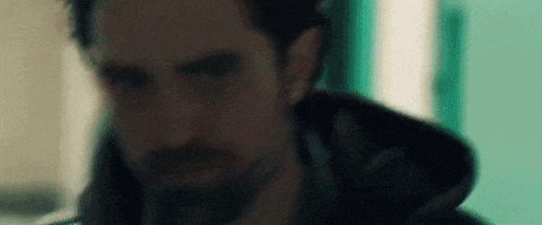 a close up of a man 's face with a beard and a hood .