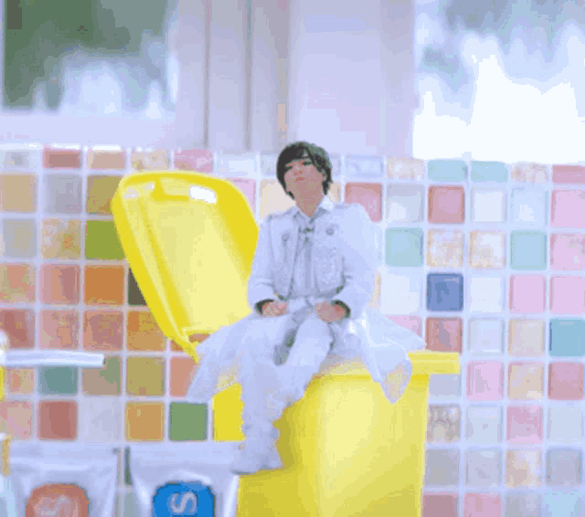 a person sitting on a yellow container with the letter s on the front