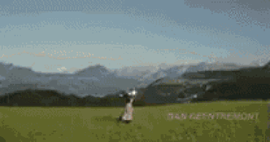 a person standing in a grassy field with mountains in the background