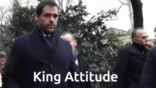 a man in a suit and tie is walking in a crowd with the words king attitude written on the bottom
