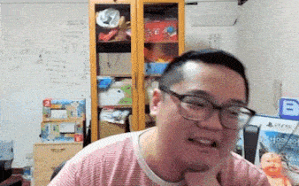 a man wearing glasses and a striped shirt is sitting in a chair in a living room .