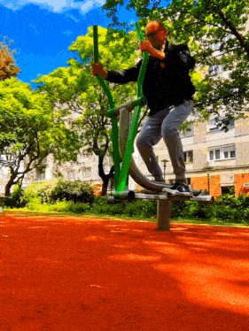 a man is riding a green machine on a red track in a park