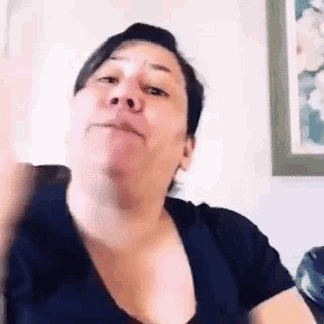 a woman is making a funny face while sitting on a couch in front of a picture .