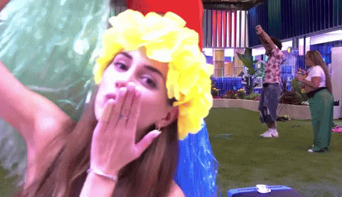 a woman wearing a yellow flower headband blows a kiss