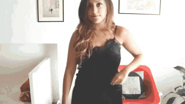 a woman in a black lace top is standing in front of a red couch