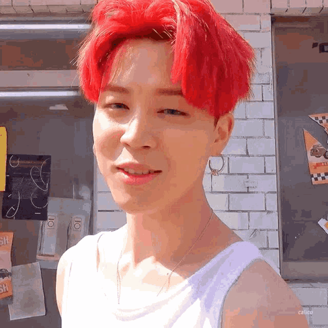 a man with red hair is wearing a white tank top and a necklace .