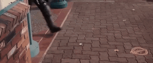 a man is walking down a brick sidewalk with a gun .