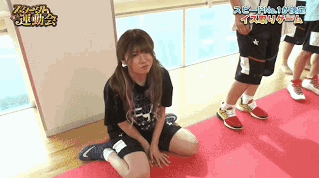 a girl is sitting on a red mat in a room with chinese writing on the wall