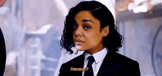a woman in a suit and tie is talking to another woman .