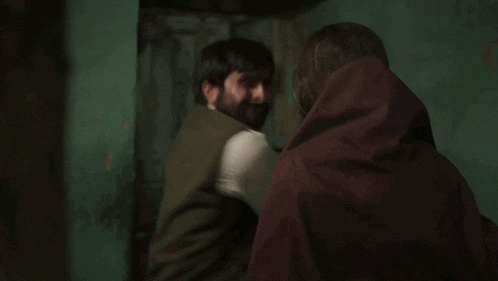 a man and a woman are standing next to each other in a dark room . the woman is wearing a head scarf .