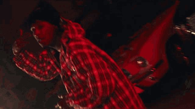 a man wearing a plaid shirt and a beanie is making a peace sign with his hands