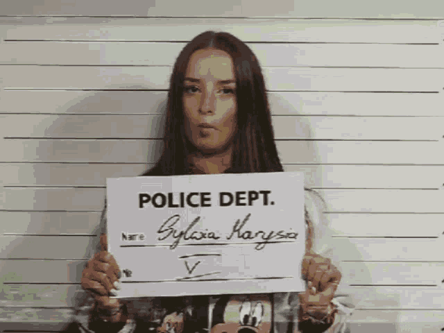 a woman is holding a sign that says police dept sylvia harysa