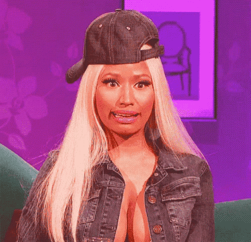 a woman wearing a baseball cap and a denim jacket is making a funny face