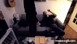 a man is sitting on a couch while another man stands next to him .