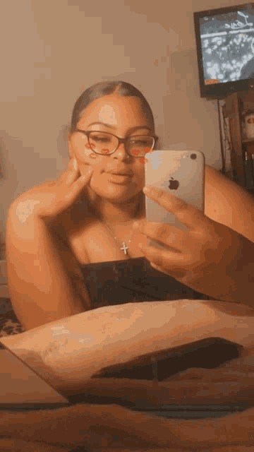 a woman wearing glasses takes a selfie with an apple phone