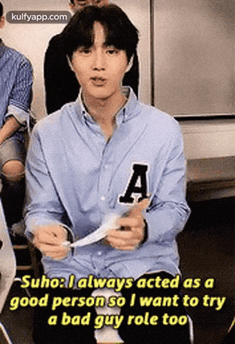 a young man in a blue shirt with the letter a on it is sitting in a room .