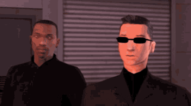 a man wearing sunglasses stands next to another man in a suit