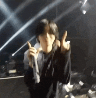 a blurry picture of a person holding a microphone and giving the middle finger .